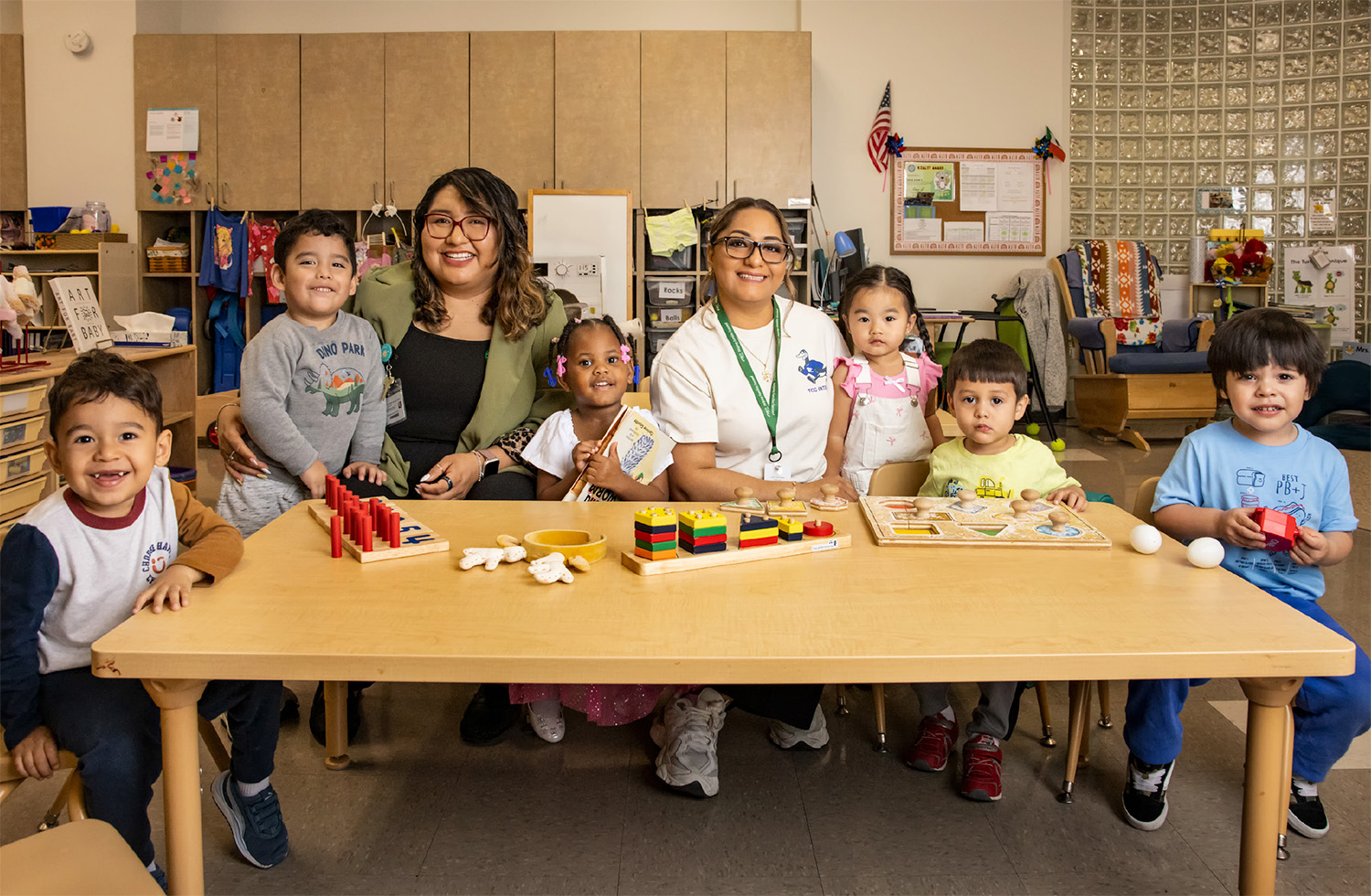 Juana Lanier sits at a table with preschool children at a childcare center.
